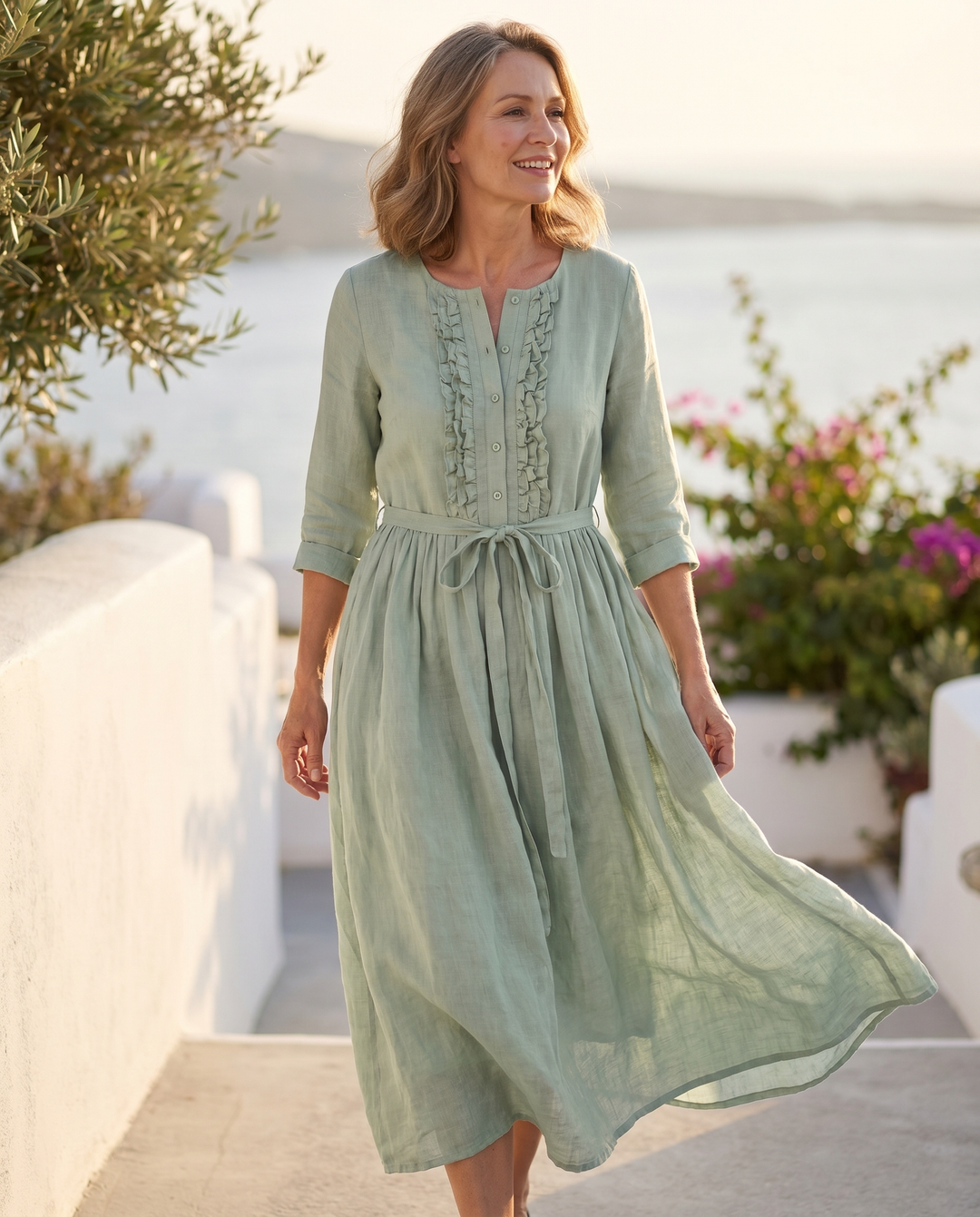 Model wearing the Karynthe dress on a sunlit coastal terrace